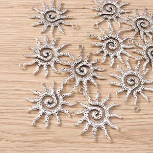 Macro detail of sun-shaped spiral jewelry pendants in vintage silver finish on wood