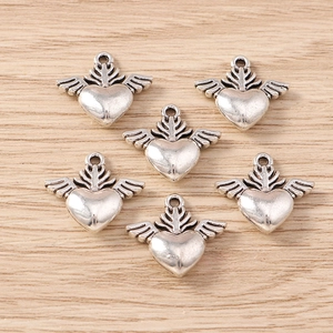 Vintage silver heart with wings charms for DIY jewelry making displayed on wood