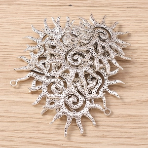 Macro detail of sun-shaped silver alloy pendants with spiral texture and wavy rays