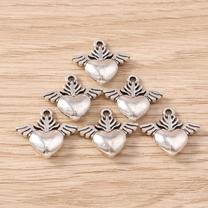 Antique silver wing heart charms for DIY jewelry making displayed on a wood background