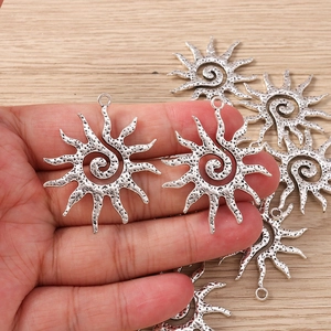 Macro detail of sun-shaped swirl charms in antique silver finish for DIY jewelry