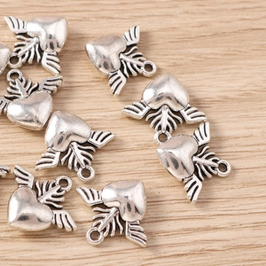 Detailed close-up of retro silver winged heart charms for DIY jewelry making and crafts