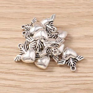 Close-up of heart-shaped wing pendants in antique silver finish for jewelry making