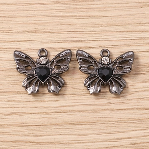Detaillierte Makroansicht schwarzer Schmetterlingsanhänger mit Herzsteinen für DIY-Schmuck