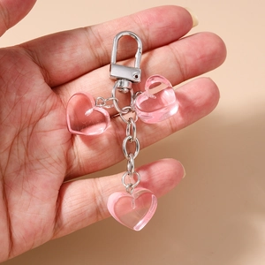 Dettaglio di tre cuori in resina rosa traslucida su un portachiavi in metallo argento