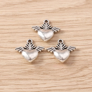 Macro detail of three vintage silver alloy heart wing pendants on a wooden background