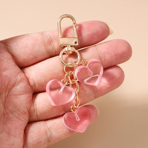 Primo piano di portachiavi a cuore rosa tenuti in mano con anelli e ganci dorati
