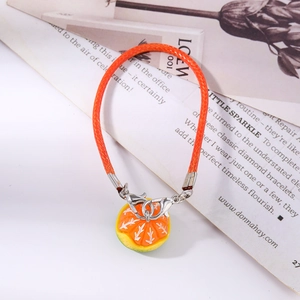 Detail of creative woven orange cord with realistic sliced resin orange charm and clasp