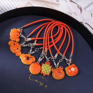 Detailed view of colorful enamel animal charms with orange woven lanyards in a blue tray