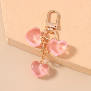 Dettaglio dei ciondoli a cuore rosa traslucido su una base di portachiavi in oro lucido