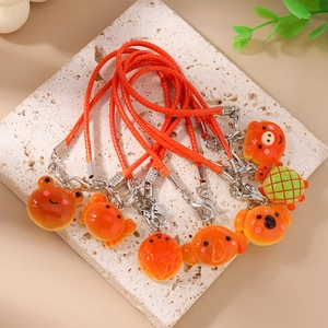 Detail view of cute animal phone charms with bright orange woven lanyards on stone base