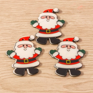Trois breloques Père Noël DIY avec trous de suspension sur fond de texture bois