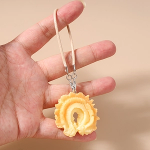 Close-up of yellow resin waffle food pendant with woven strap and metal clip