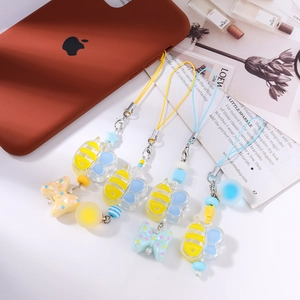 Detail of bee and butterfly resin phone charms with striped beads on a trendy phone case