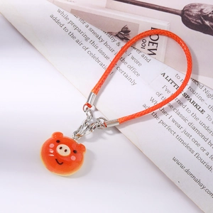 Close-up of orange braided cord and cute pig charm for phone or bag accessory