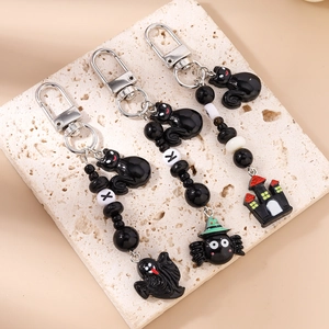Halloween beaded keychains with ghost cat and spider charms on stone background