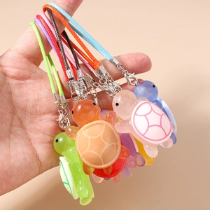 Detail showing colorful resin turtle phone charms with braided straps and metal lobster clasps