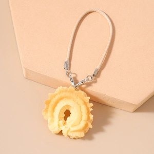 Detailed view of the woven beige cord and fruit-shaped resin pendant with silver lobster clasp