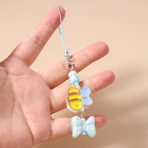 Close-up of cartoon bee pendant and pink polka dot bow on blue mobile phone strap