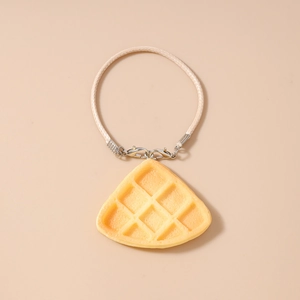 Detailed view of a realistic waffle pendant charm with beige woven cord and silver clasp