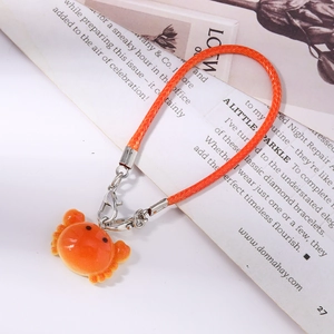Detail of a bright orange crab pendant with leather braided cord and silver metal clasp