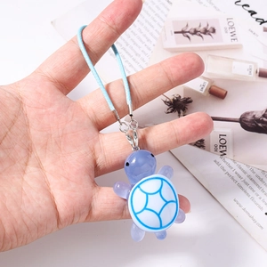 Close-up of cute purple turtle phone charm with blue woven lanyard and silver lobster clasp