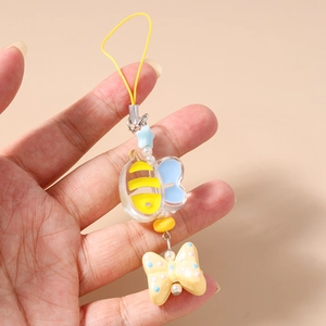 Detailed view of a cartoon bee charm with yellow stripes, blue wings and a polka dot bow