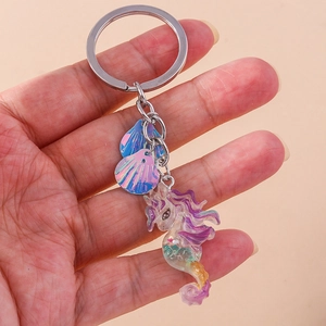 Detail of iridescent resin unicorn seahorse keychain with silver rings and shell charms