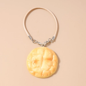 Close-up of realistic pineapple bun charm with beige braided rope and silver clasps