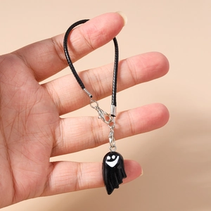 Detail of cute black ghost phone charm with white face and silver metal clasp