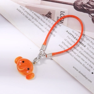 Orange braided phone strap with a glossy cartoon blob character charm and silver clasp