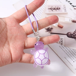Detailed close-up of a purple resin turtle charm with a woven strap and silver clasp