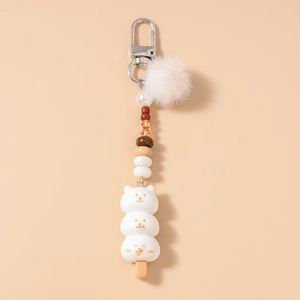 Détail d'un porte-clés dango ours mignon avec pompon en peluche et perles colorées sur fermoir