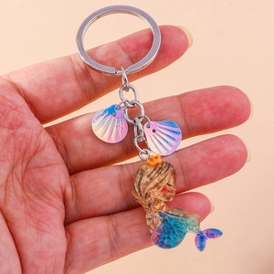 Close-up of a mermaid keychain with iridescent shells and blue-purple glitter resin tail