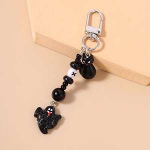 Detail of beaded keychain featuring black ghost and cat charms with metal clasp