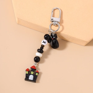 Detail of Halloween keychain with black cat charm, beaded strap and spooky castle pendant