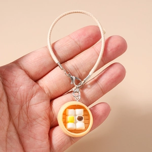 Detailed close-up of a miniature dim sum steamer pendant with a woven cord and lobster clasp