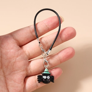 Detail of cartoon black spider phone charm with a green hat and silver lobster clasp