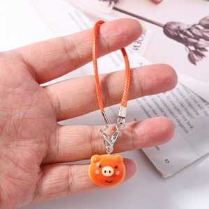 Close-up of cute orange pig resin charm with woven lanyard and silver lobster clasp