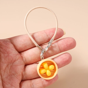 Close-up of handmade dumpling charm with leather strap held in hand for size visualization