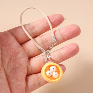 Detailed close-up of a mini dumpling steamer keychain with white woven hand strap