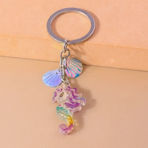 Detail of holographic blue shells and colorful seahorse charm on a silver keychain