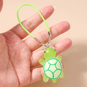 Detailed close-up of a green resin turtle charm held by hand for mobile phone or bag