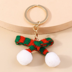 Knitted red and green striped bow keychain with white plush pom-poms on golden ring