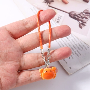 Detail of orange crab bag charm with matching woven lanyard and metal lobster clasp