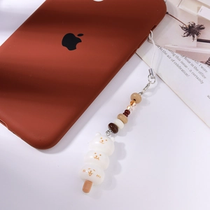 Détail de trois breloques chat empilées sur un cordon de téléphone avec des perles