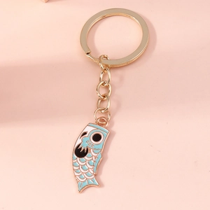 Close-up of a light blue cartoon koi fish flag keychain on a soft pink background