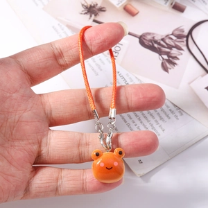 Detail of orange frog charm with woven strap and lobster clasp held by hand