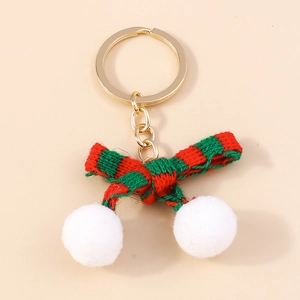 Close-up of a festive knit bow with white plush pom-poms and gold metal keychain ring