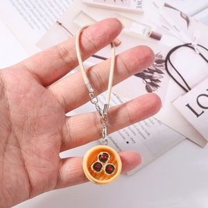 Macro shot of realistic food charm featuring a siu mai dumpling with woven lanyard strap